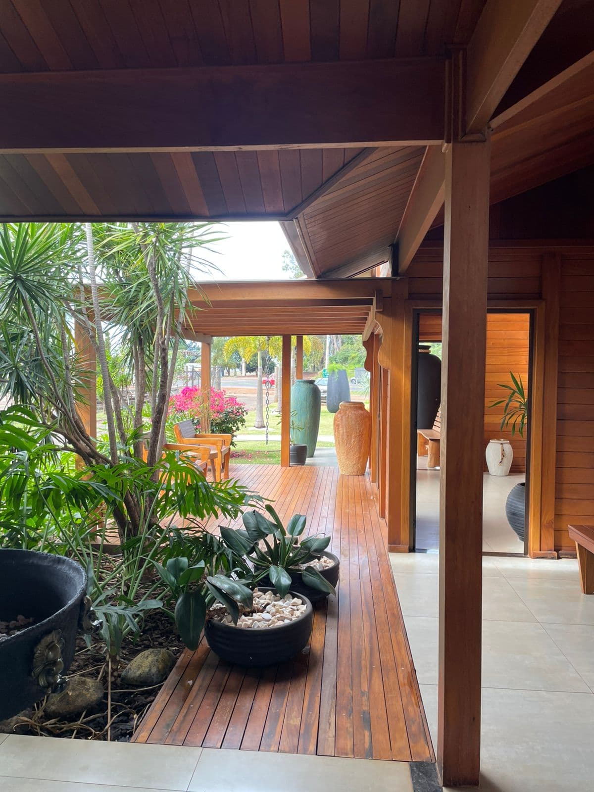 Varanda com paisagismo em uma casa de madeira realizada pela empresa